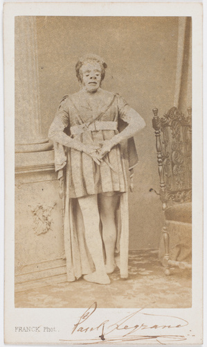 Franck - Paul Legrand en habit de scène, debout, de dos, portant un masque à l'a...