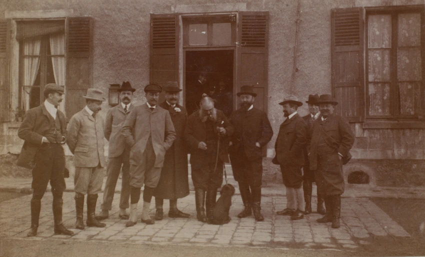 Anonyme - Un groupe d'hommes posant devant une maison
