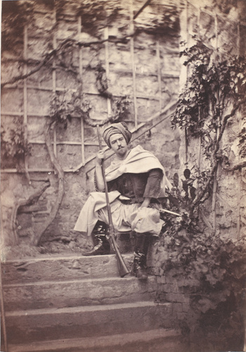 Achille Bonnuit - Homme déguisé en zouave, assis sur la marche d'un escalier