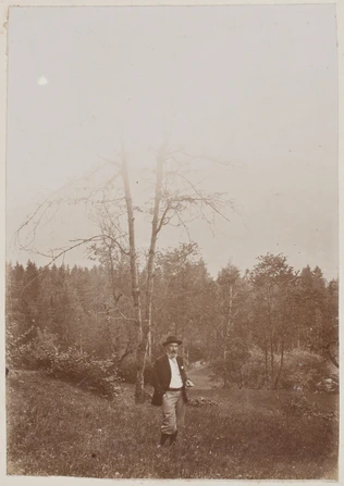 Anonyme - Henry Lerolle debout dans un champ, au fond un paysage boisé