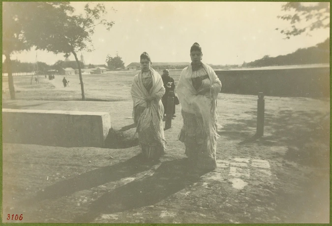 Anonyme - Deux femmes marchant, vue d'un chemin vers la ville au fond