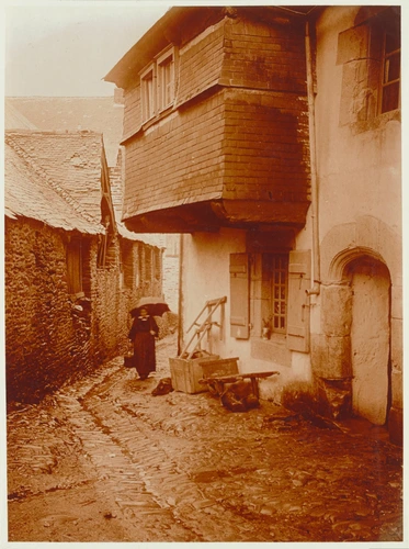 Carhaix-Plouguer ?, femme avec parapluie dans une rue aux vieilles maisons - Charles Augustin Lhermitte