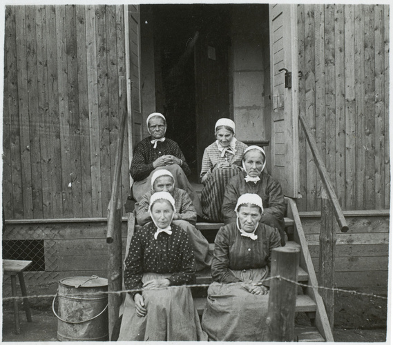André de Boudinhon - Six femmes assises sur les marches devant la porte du camp ...