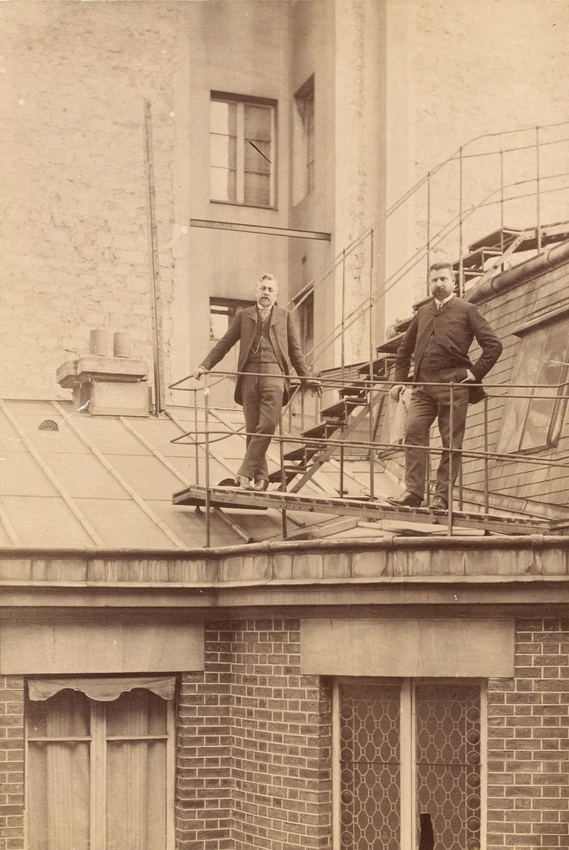 G. Eiffel et un homme barbu, debout au pied d'un escalier métallique extérieur, au laboratoire Eiffel - Gustave Eiffel