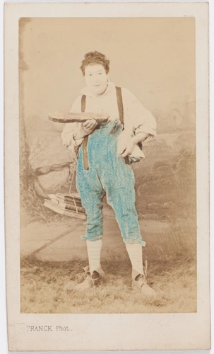 Paul Legrand en habit de scène (paysan), debout, tenant une tranche de pain et un paquet de livres - Franck