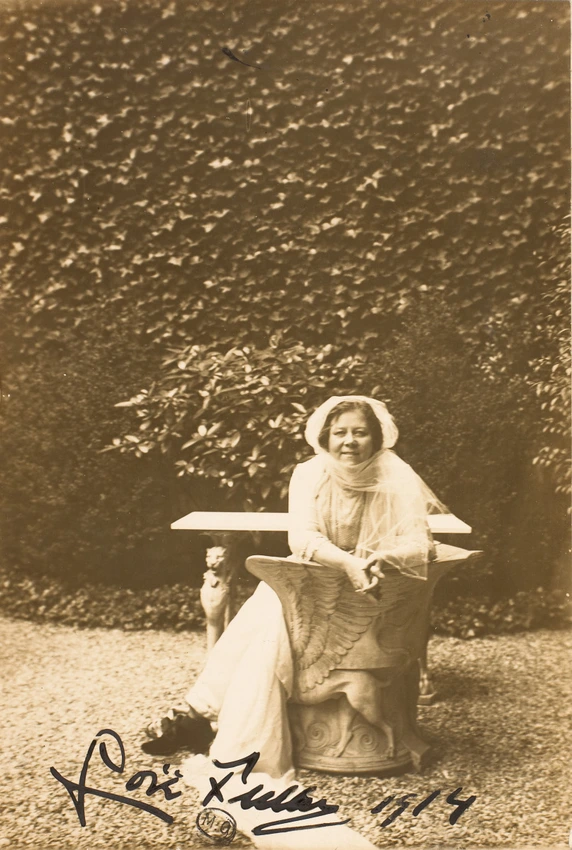 Loïe Fuller assise dans un jardin, sur un siège en pierre à l'antique avec taureau assyrien - Harry C. Ellis