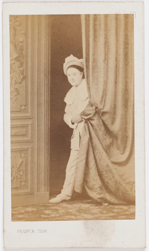 Paul Legrand en habit de scène (Pierrot), debout de face et semblant émerger de derrière un rideau - Franck