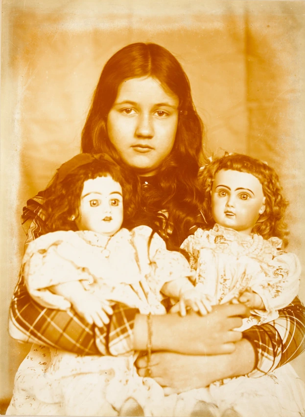 Denise assise, deux poupées serrées dans les bras - Emile Zola
